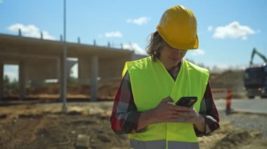 İnşaatçı inşaat alanındaki akıllı telefona SMS yazıyor..