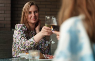 İki arkadaş tatilde balkonda şarap içiyor..