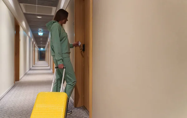 Woman with suitcase opens the door to the hotel room. Check in at the hotel.