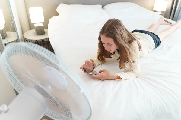 Teenager Leží Telefonem Před Chladícím Ventilátorem — Stock fotografie