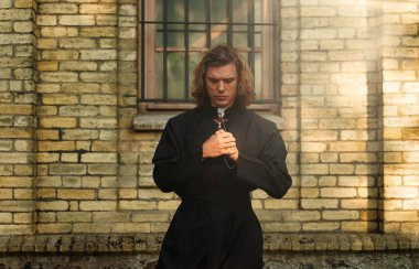 Kilisenin yanında haçlı dua eden Hıristiyan rahip..