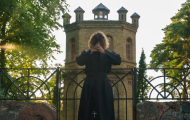 Kilisenin yanında haçlı dua eden Hıristiyan rahip..