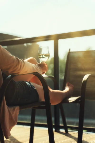 女人坐在阳台上享用白葡萄酒 — 图库照片