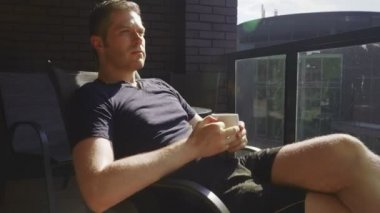 Balkonda bir fincan kahveli bir adam..