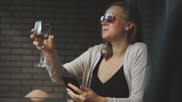 女性はワインを飲み バルコニーテラスで携帯電話を使用して — ストック動画