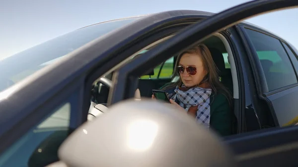 Kvinnan Sitter Bilen Och Använder Mobiltelefon — Stockfoto