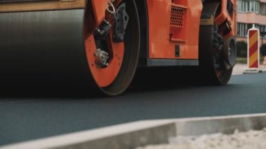 Yol yenileme. Ağır titreşimli yol silindiri sıcak asfalt yığıyor.