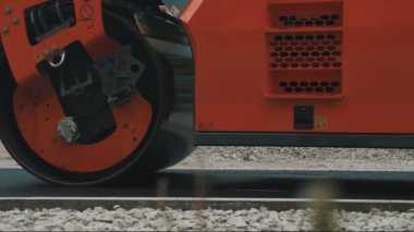 Yol yenileme. Ağır titreşimli yol silindiri sıcak asfalt yığıyor.