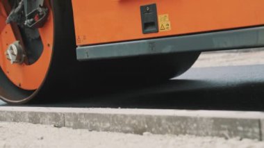 Yol yenileme. Ağır titreşimli yol silindiri sıcak asfalt yığıyor.