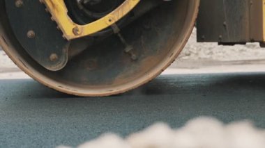 Yol yenileme. Ağır titreşimli yol silindiri sıcak asfalt yığıyor.