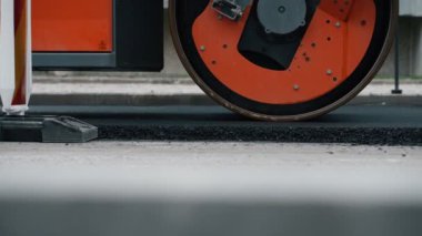 Yol yenileme. Ağır titreşimli yol silindiri sıcak asfalt yığıyor.