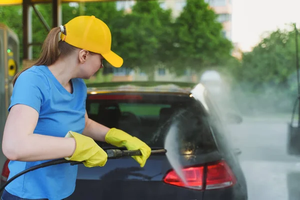 妇女在制服清洗车使用高压水 洗车服务 — 图库照片