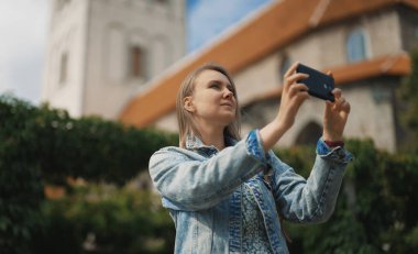 Akıllı telefonlu bir kadın eski şehrin fotoğraflarını çekiyor..
