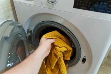 Adam çamaşır makinesine havlu yüklüyor..