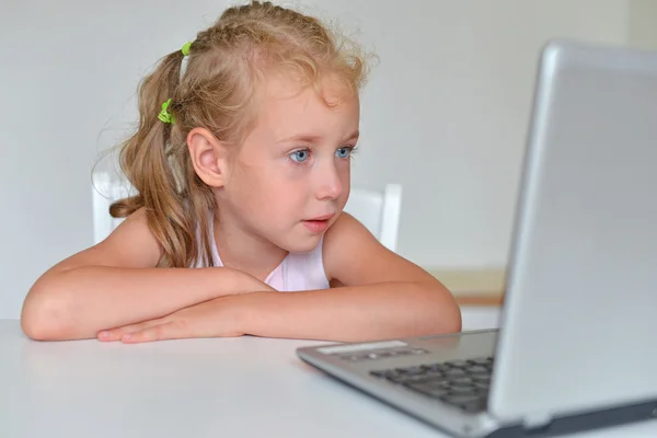 Liten flicka tittar på tecknad film på datorn. — Stockfoto