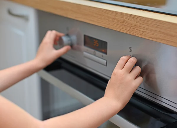 Gevaarlijke situatie in de keuken. kind spelen met elektrische oven. — Stockfoto