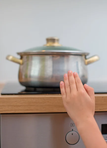 Criança toca panela quente no fogão. Situação perigosa em casa . — Fotografia de Stock