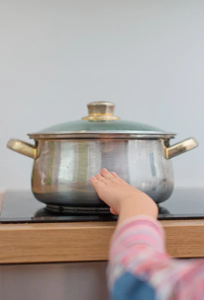 Ребенок касается горячей сковороды на плите. Опасная ситуация дома . — стоковое фото