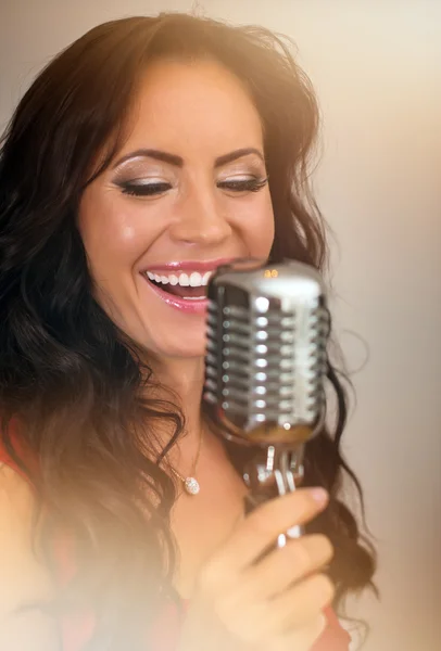 Attractive brunette woman singing into vintage microphone. — Stock Photo, Image