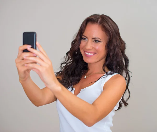 Aantrekkelijke brunette nemen selfie met cellphone. — Stockfoto