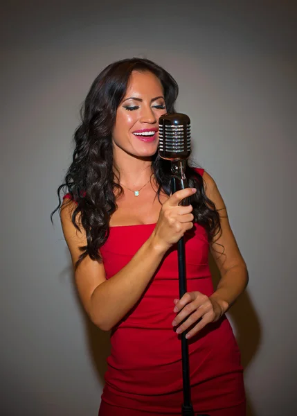 Attraente donna bruna che canta in microfono vintage . — Foto Stock