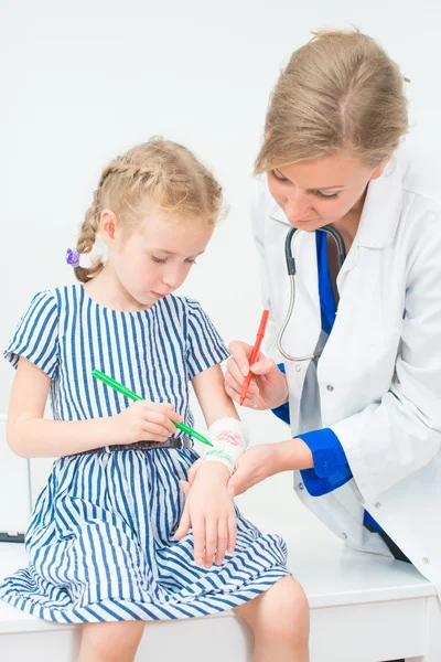 Arzt und kleines Mädchen zeichnen Verband mit Filzspitze. Spieltherapiekonzept. — Stockfoto