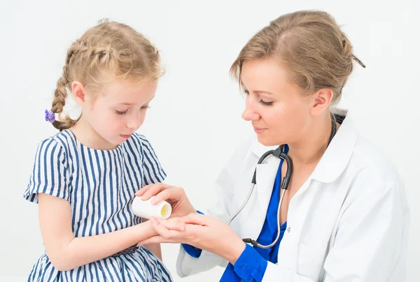 Female doctor giving vitamins to little girl. — Stock Photo, Image