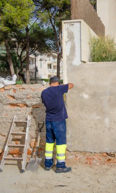 Worker embeds concrete wall outdoors. Renovation works. clipart