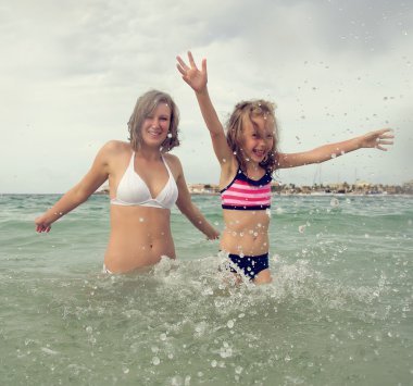 Kadın ve kızı denizde eğleniyorlar..