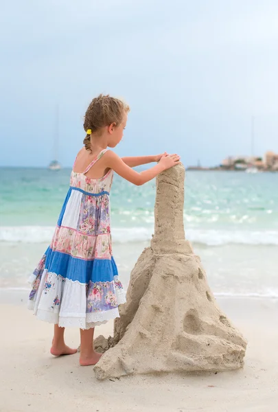 Bambina con castello di sabbia sulla spiaggia . — Foto Stock