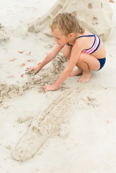 Маленькая девочка играет на пляже. Песочный крокодил . — стоковое фото