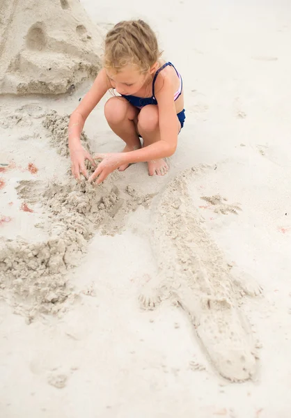 Meisje spelen op het strand. Gebouw zand krokodil. — Stockfoto