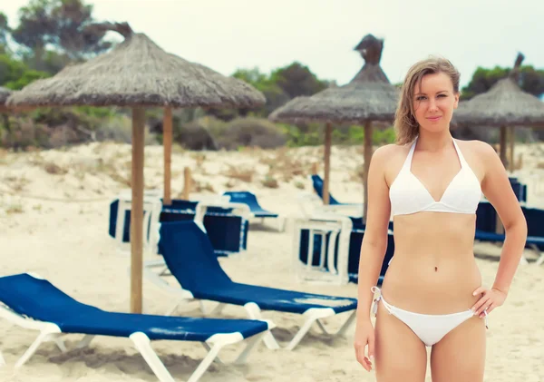 Attraktive Frau am Strand mit Liegestühlen. — Stockfoto