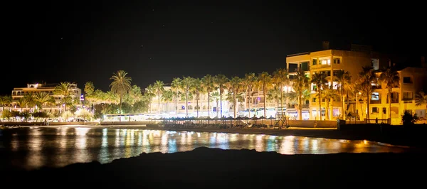 Nacht stad met palmen in de buurt van het strand. — Stockfoto