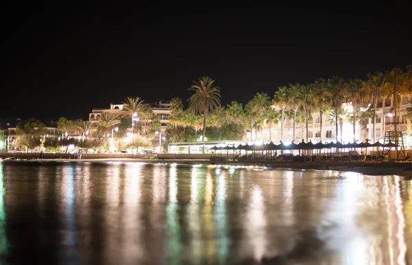 Nacht stad met palmen in de buurt van het strand. — Stockfoto
