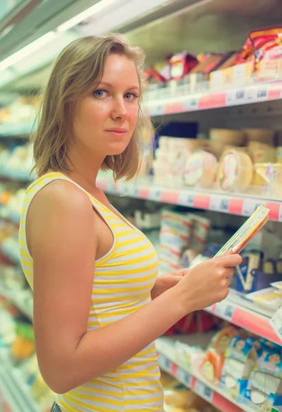 Молодая женщина выбирает мясо в продуктовом магазине . — стоковое фото