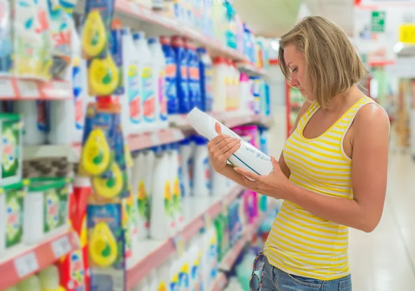 Frau wählt Waschmittel im Supermarkt. — Stockfoto