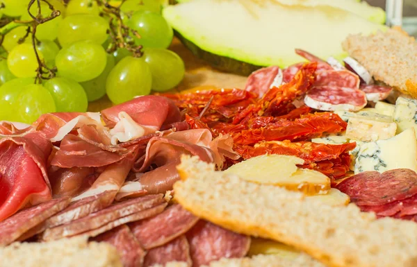 Geschnittener Schinken, Käse, Brot und Trauben. — Stockfoto