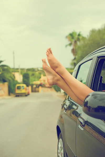 Woman's legs out of the car window. Vintage effect photo. — Stock Photo, Image