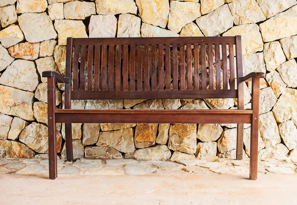 Pouliční dřevěná lavička proti cihlové zdi. — Stock fotografie
