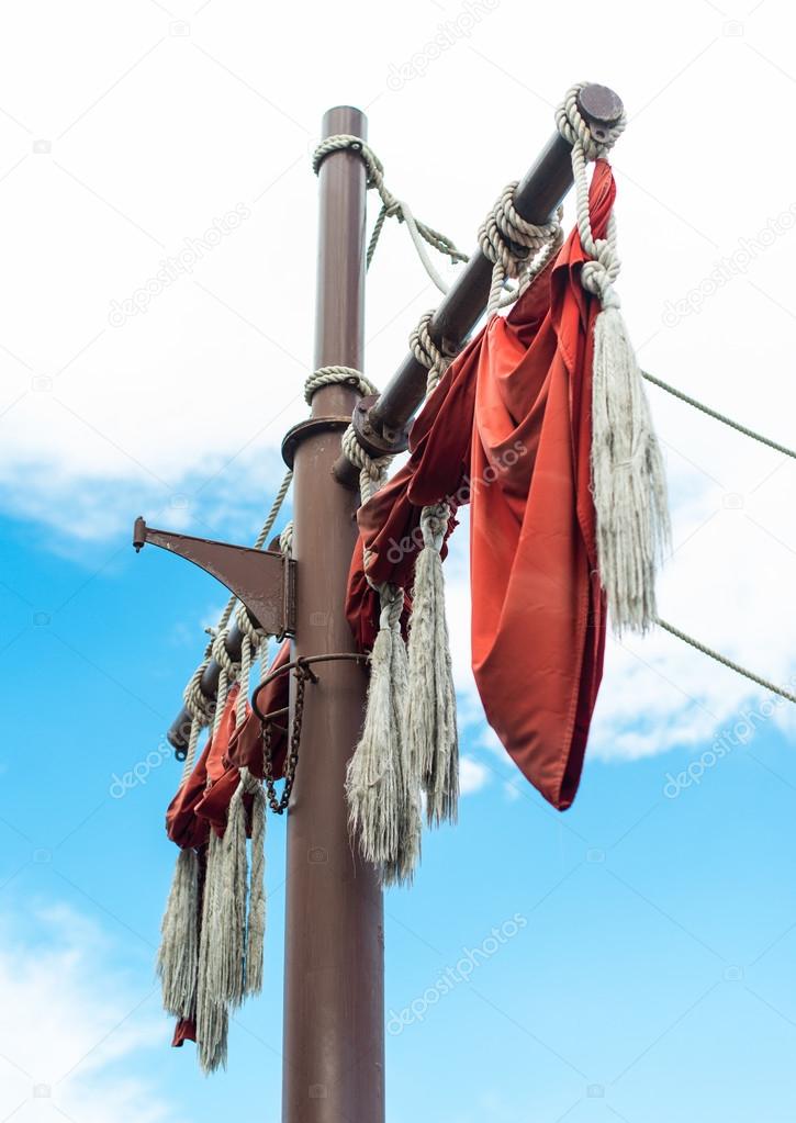 Old sailing ship masts with red sails.