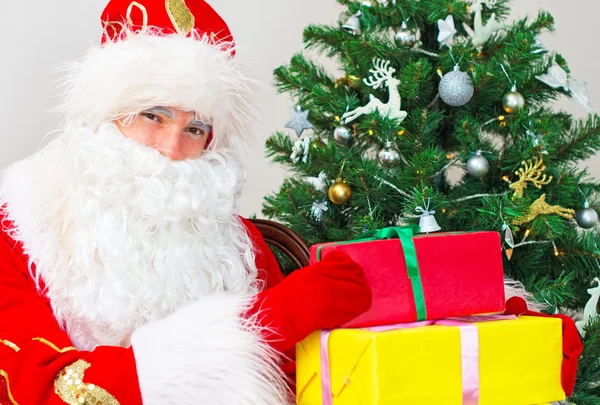 Weihnachtsmann mit Geschenken am Weihnachtsbaum. — Stockfoto