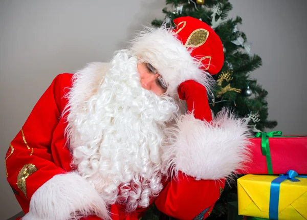 Santa Claus durmiendo junto al árbol de Navidad y regalos . — Foto de Stock