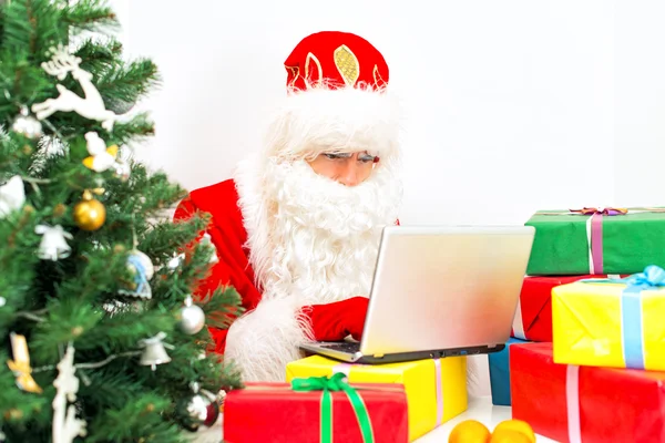 Santa Claus está utilizando el ordenador portátil en su taller . — Foto de Stock