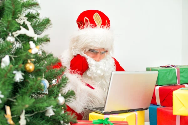 Santa Claus está utilizando el ordenador portátil en su taller . —  Fotos de Stock