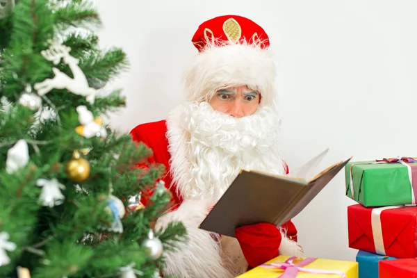 Santa Claus verificando la lista de deseos en su taller . — Foto de Stock