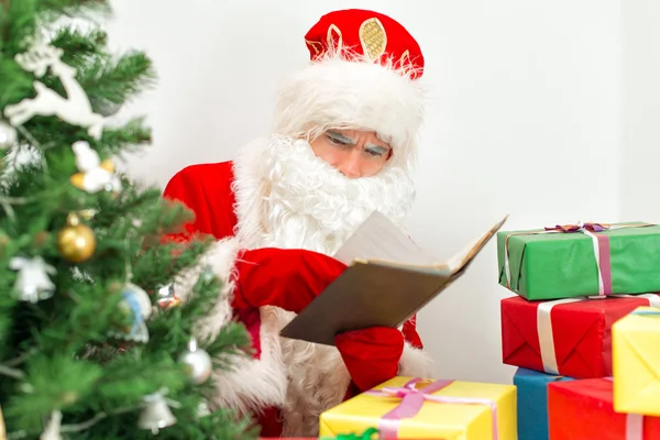 Santa Claus sprawdzania listy życzeń w swoim warsztacie. — Zdjęcie stockowe