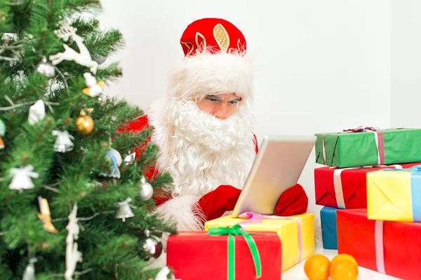 Santa Claus está utilizando la tableta PC en su taller . — Foto de Stock