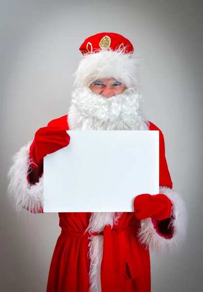 Bad Santa Claus is holding white blank. — Stock Photo, Image