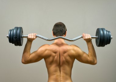 Kaslı adam barbell ile yapıyor. Arkadan Görünüm.